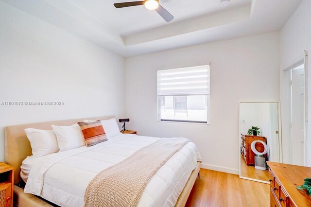 10602 W 33rd Way, Hialeah, FL 33018 - bedroom with light wood-style floors, a tray ceiling, baseboards, and ceiling fan