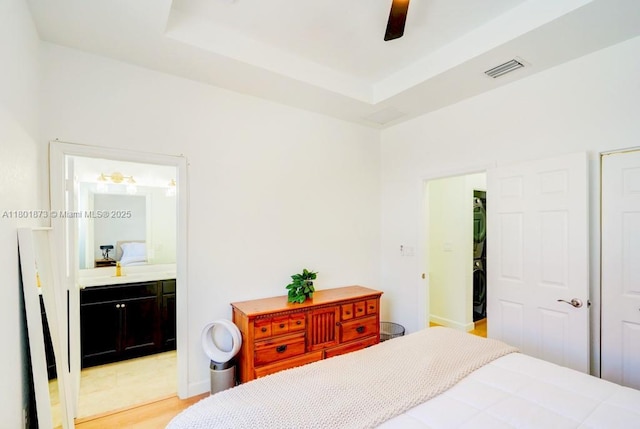 10602 W 33rd Way, Hialeah, FL 33018 - bedroom with estacked washer and dryer, ensuite bath, light wood-style floors, and a raised ceiling
