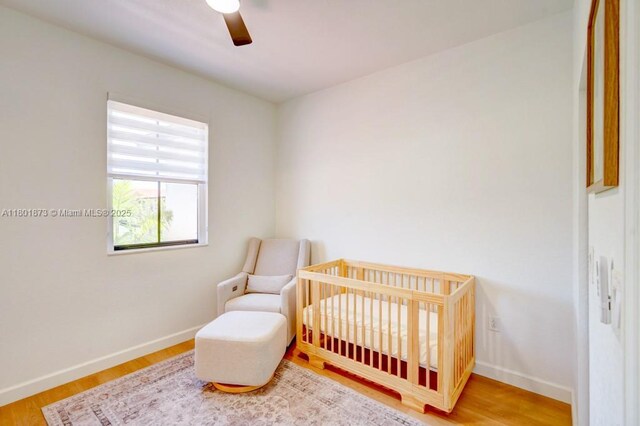 10602 W 33rd Way, Hialeah, FL 33018 - bedroom featuring baseboards, a crib, wood finished floors, and ceiling fan