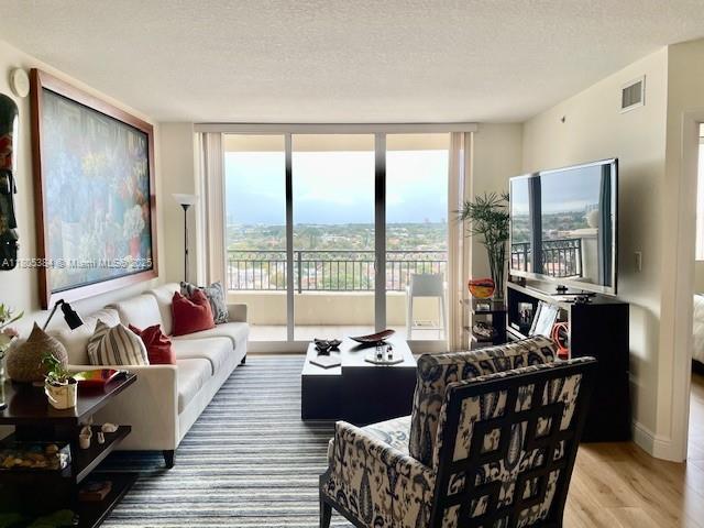 3232 SW 22nd Ter Unit 1303, Miami, FL 33145 - living room featuring wood finished floors, a textured ceiling, and floor to ceiling windows