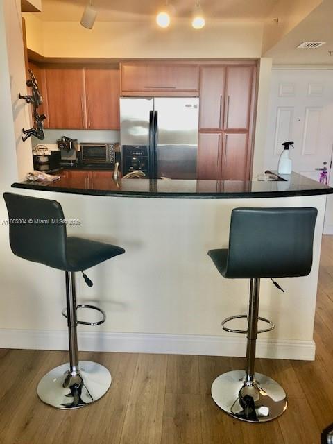 3232 SW 22nd Ter Unit 1303, Miami, FL 33145 - kitchen with stainless steel fridge with ice dispenser, dark countertops, a peninsula, a breakfast bar area, and wood finished floors