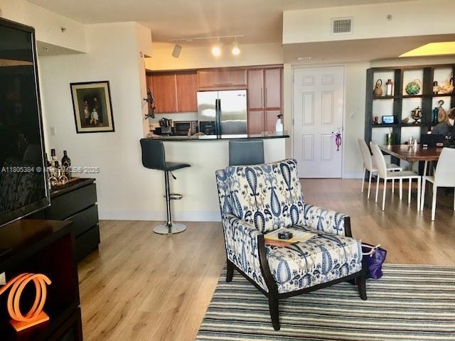 3232 SW 22nd Ter Unit 1303, Miami, FL 33145 - kitchen featuring stainless steel fridge with ice dispenser, dark countertops, light wood finished floors, and brown cabinets