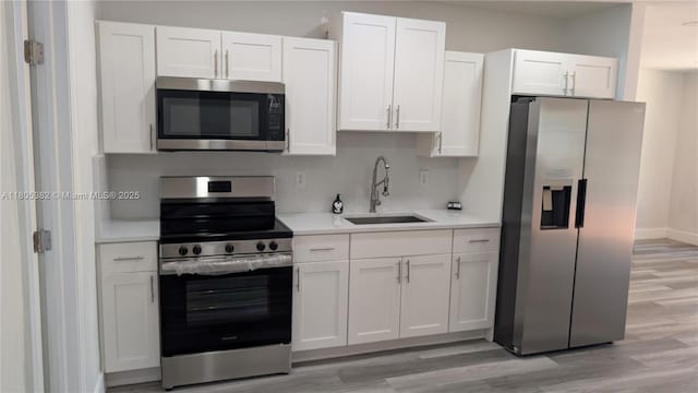 3601 N 72nd Ave, Hollywood, FL 33024 - kitchen featuring stainless steel appliances, a sink, white cabinetry, light countertops, and light wood finished floors