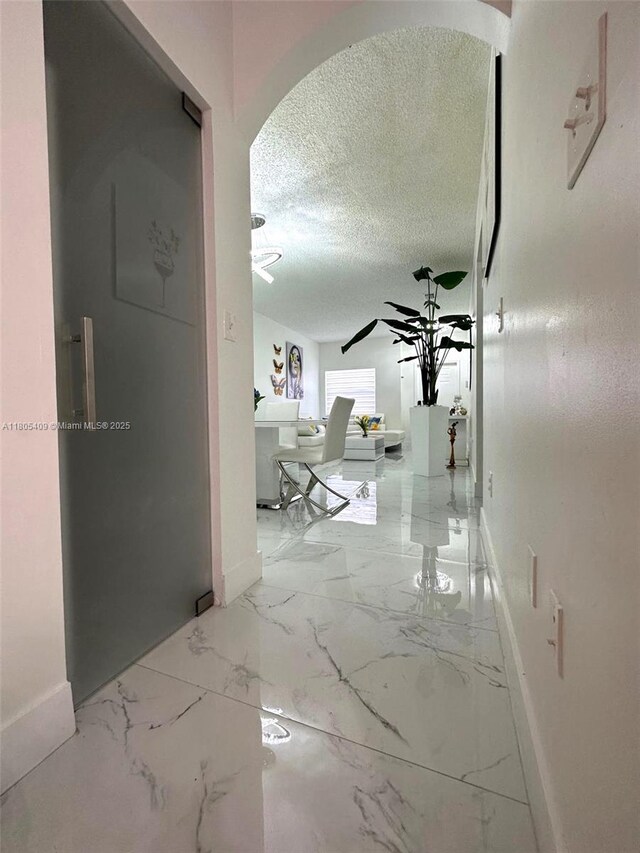 2207 SE 23rd Ave Unit 2207, Homestead, FL 33035 - hallway with baseboards, a textured ceiling, arched walkways, and marble finish flooring