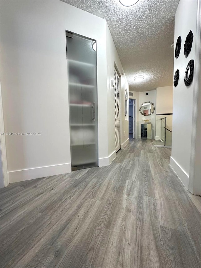 2207 SE 23rd Ave Unit 2207, Homestead, FL 33035 - hallway with wood finished floors, a textured ceiling, baseboards, and elevator
