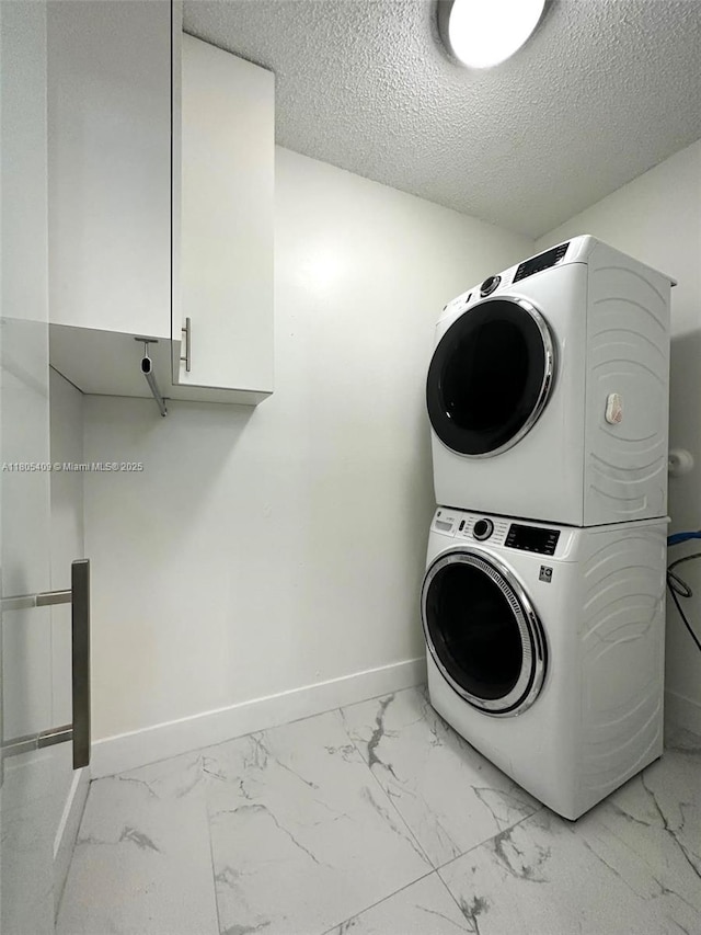 2207 SE 23rd Ave Unit 2207, Homestead, FL 33035 - laundry room with stacked washer and clothes dryer, light marble finish flooring, cabinet space, baseboards, and a textured ceiling