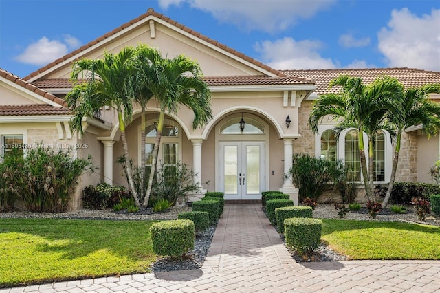5630 N Sterling Ranch Dr, Davie, FL 33314 - view of front of home with french doors, stucco siding, a front lawn, a tile roof, and stone siding