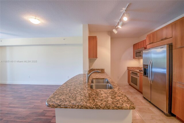 510 NW 84th Ave Unit 303, Plantation, FL 33324 - kitchen with stainless steel appliances, a sink, brown cabinetry, track lighting, and a textured ceiling