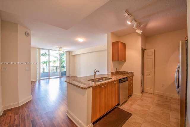 510 NW 84th Ave Unit 303, Plantation, FL 33324 - kitchen with stainless steel appliances, a sink, rail lighting, brown cabinets, and light stone countertops