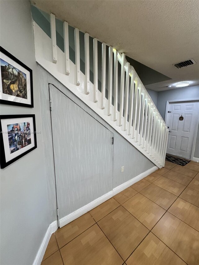 7005 NW 173rd Dr Unit 1702, Hialeah, FL 33015 - stairway featuring tile patterned floors, baseboards, and a textured ceiling