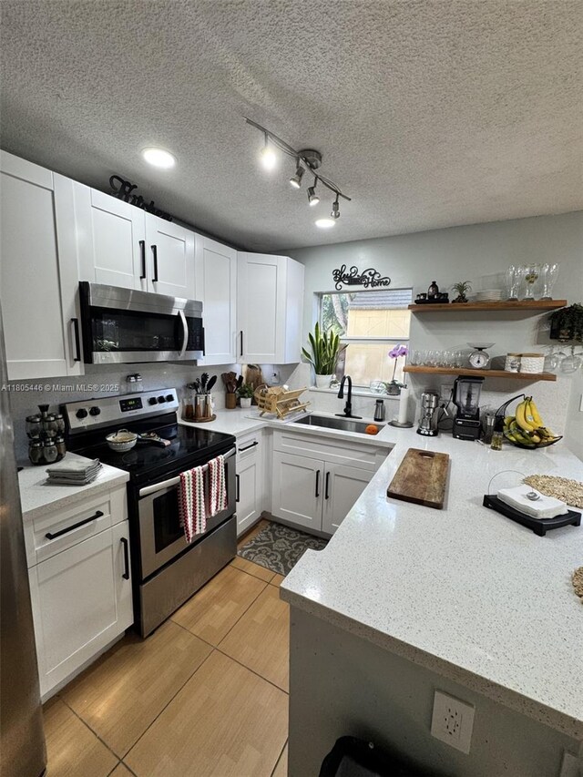 7005 NW 173rd Dr Unit 1702, Hialeah, FL 33015 - kitchen featuring appliances with stainless steel finishes, white cabinets, a sink, light stone countertops, and a textured ceiling