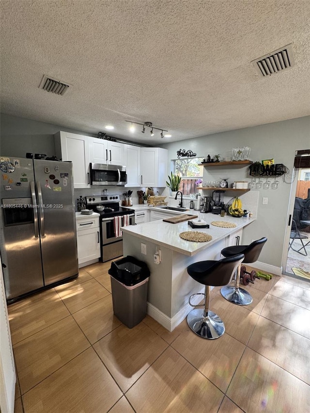 7005 NW 173rd Dr Unit 1702, Hialeah, FL 33015 - kitchen featuring stainless steel appliances, a sink, a peninsula, light tile patterned floors, and a textured ceiling