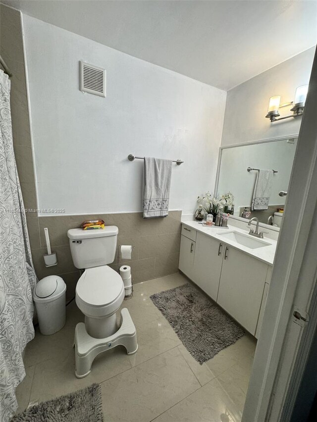 7005 NW 173rd Dr Unit 1702, Hialeah, FL 33015 - full bath featuring toilet, vanity, marble look tile flooring, tile walls, and wainscoting