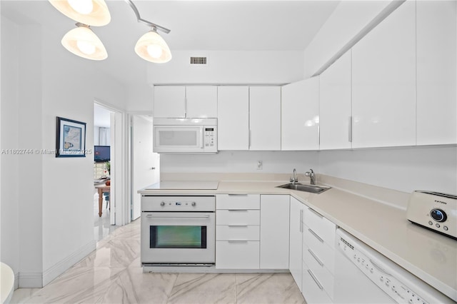 5700 Collins Ave Unit 7G, Miami Beach, FL 33140 - kitchen with white appliances, a sink, white cabinets, light marble finish floors, and light countertops