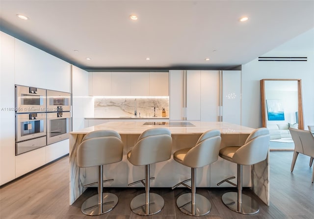 10203 Collins Ave Unit 302, Bal Harbour, FL 33154 - kitchen with modern cabinets, tasteful backsplash, white cabinetry, light wood finished floors, and a large island