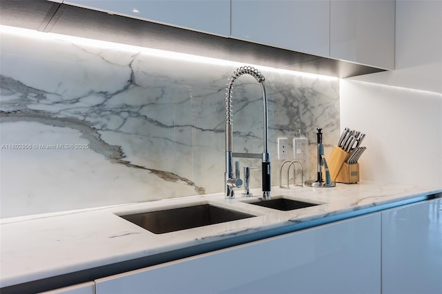 10203 Collins Ave Unit 302, Bal Harbour, FL 33154 - kitchen view of a sink, backsplash, light stone countertops, and white cabinets