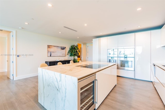 10203 Collins Ave Unit 302, Bal Harbour, FL 33154 - kitchen featuring wine cooler, black electric cooktop, light wood finished floors, white cabinets, and recessed lighting