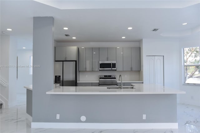 2925 SW 133rd Ave, Miramar, FL 33027 - kitchen with stainless steel appliances, gray cabinetry, a sink, light marble finish flooring, and baseboards