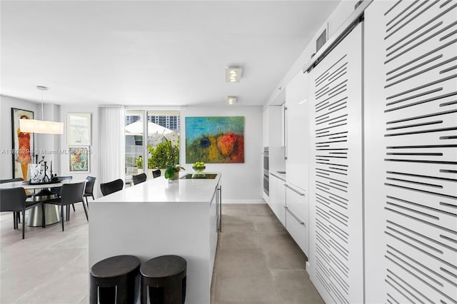 1201 20th St Unit 314, Miami Beach, FL 33139 - kitchen featuring white cabinets, a center island, a sink, hanging light fixtures, and light countertops