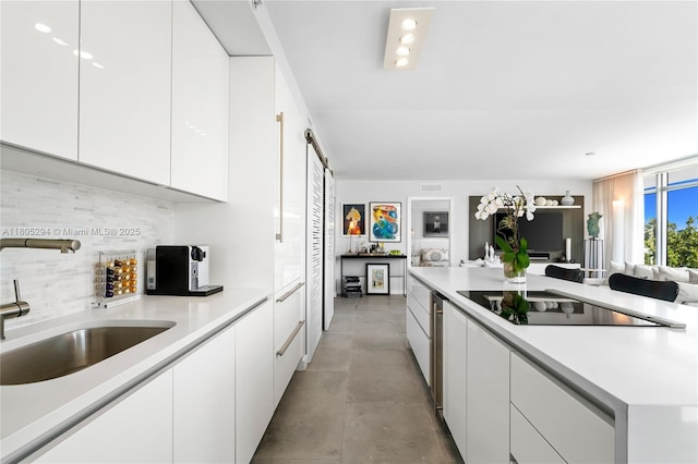 1201 20th St Unit 314, Miami Beach, FL 33139 - kitchen featuring black electric stovetop, a sink, open floor plan, white cabinetry, and decorative backsplash