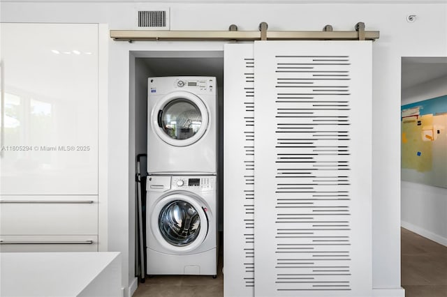1201 20th St Unit 314, Miami Beach, FL 33139 - washroom featuring estacked washer and dryer, a barn door, tile patterned flooring, and baseboards
