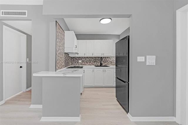 1150 Euclid Ave Unit 305, Miami Beach, FL 33139 - kitchen featuring freestanding refrigerator, white cabinets, tasteful backsplash, and a peninsula