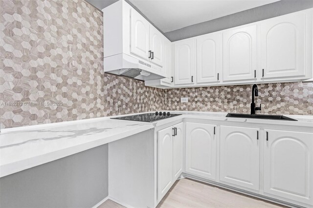 1150 Euclid Ave Unit 305, Miami Beach, FL 33139 - kitchen featuring black electric cooktop, ventilation hood, light stone counters, white cabinetry, and light wood-style flooring