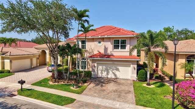 5957 NW 125th Ave, Coral Springs, FL 33076 - mediterranean / spanish-style home featuring decorative driveway, stucco siding, a tiled roof, a front lawn, and an attached garage