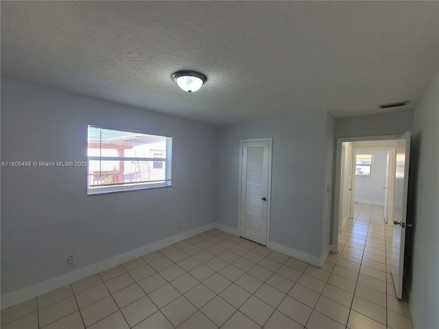 4519 NW 49th Dr, Tamarac, FL 33319 - spare room with baseboards, light tile patterned floors, and a textured ceiling