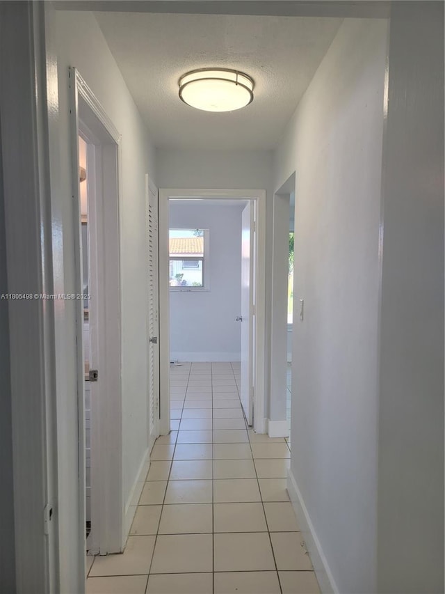 4519 NW 49th Dr, Tamarac, FL 33319 - hallway with light tile patterned floors, baseboards, and a textured ceiling