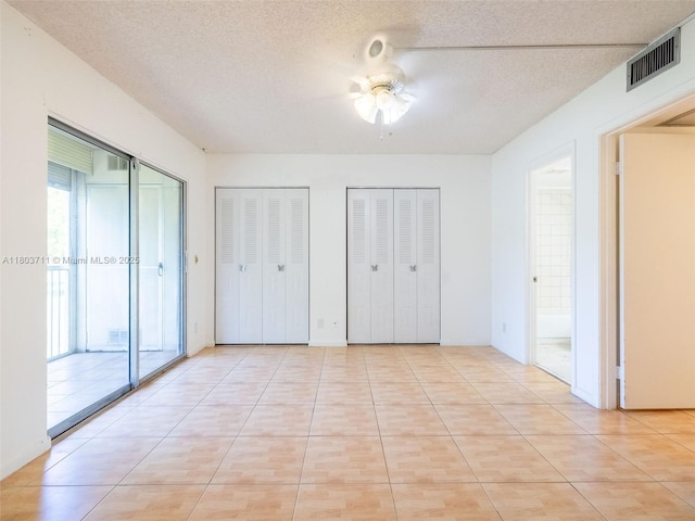 13250 SW 7th Ct Unit 208L, Pembroke Pines, FL 33027 - unfurnished bedroom with two closets, a ceiling fan, connected bathroom, and a textured ceiling