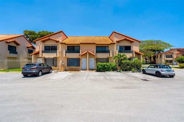 view of front of property with a tile roof, uncovered parking, and stucco siding
