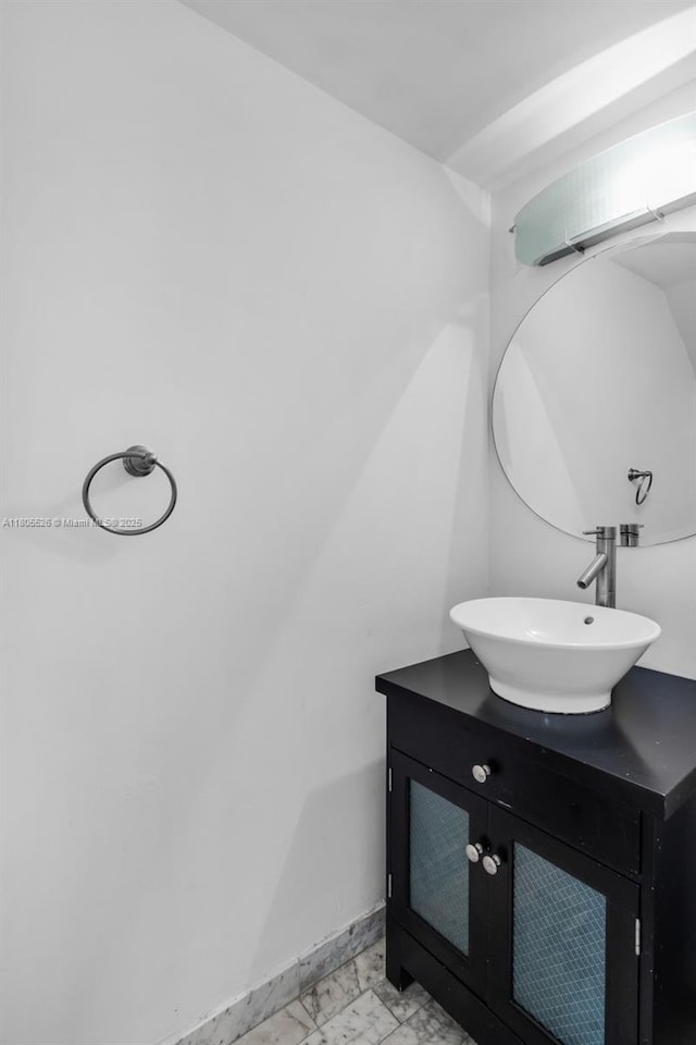 bathroom with vanity, marble look tiles, and baseboards