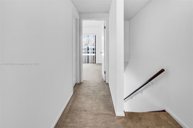 corridor with carpet floors, an upstairs landing, and baseboards