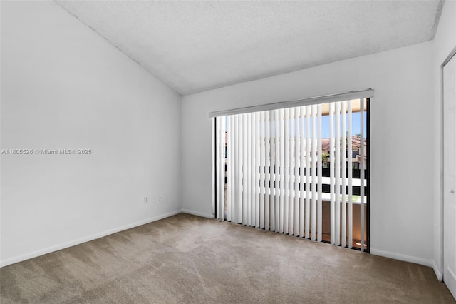 carpeted spare room with lofted ceiling, baseboards, and a textured ceiling