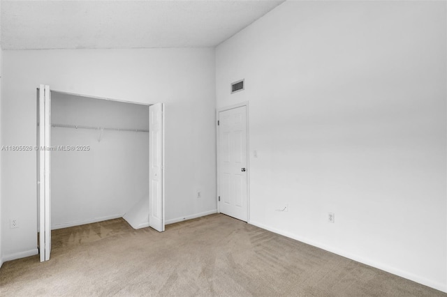 unfurnished bedroom featuring carpet flooring, lofted ceiling, baseboards, and a closet