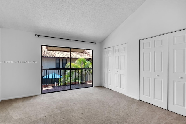 unfurnished bedroom featuring a textured ceiling, multiple closets, carpet floors, access to exterior, and lofted ceiling