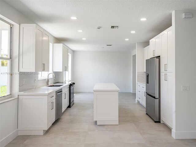 1128 Hidden Valley Way, Weston, FL 33327 - kitchen with appliances with stainless steel finishes, a sink, a kitchen island, baseboards, and light countertops