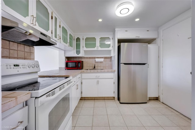 1551 NE Miami Gardens Dr Unit 322, Miami, FL 33179 - kitchen with white electric range, freestanding refrigerator, under cabinet range hood, light countertops, and decorative backsplash