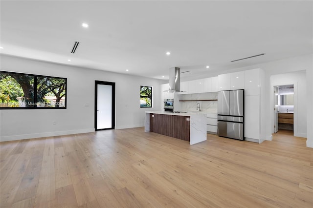 53 NW 107th St, Miami Shores, FL 33168 - kitchen with modern cabinets, ventilation hood, stainless steel fridge, a center island, and white cabinets