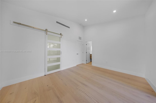 53 NW 107th St, Miami Shores, FL 33168 - empty room with light wood-type flooring, recessed lighting, and a barn door