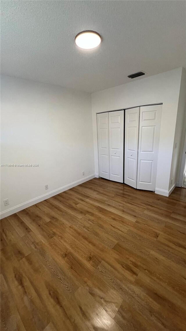 2615 Spiceberry Ln Unit 2625, Boynton Beach, FL 33436 - unfurnished bedroom with wood finished floors, a textured ceiling, and a closet