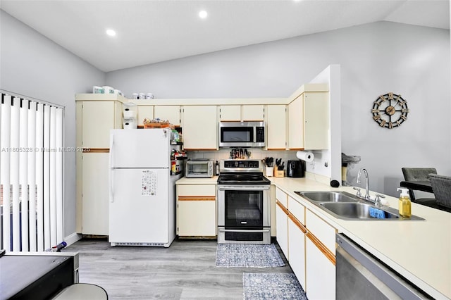 1054 NW 53rd St, Deerfield Beach, FL 33064 - kitchen featuring appliances with stainless steel finishes, a sink, vaulted ceiling, light countertops, and light wood-style flooring