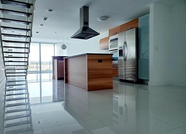 2950 NE 188th St Unit 444, Aventura, FL 33180 - kitchen featuring wall chimney exhaust hood, stainless steel fridge, light tile patterned floors, floor to ceiling windows, and wall oven