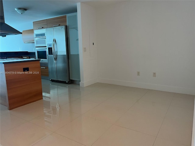 2950 NE 188th St Unit 444, Aventura, FL 33180 - kitchen with stainless steel fridge with ice dispenser, range hood, dark countertops, baseboards, and light tile patterned flooring