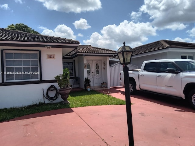view of front of home featuring stucco siding, a tiled roof, and concrete driveway