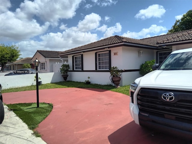 view of side of property featuring a tile roof, stucco siding, and fence