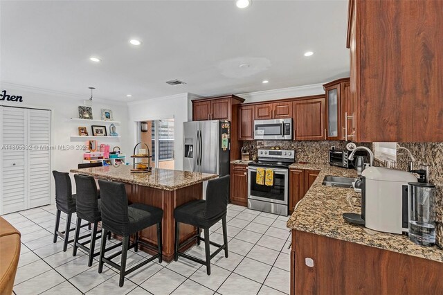 16401 SW 94th St, Miami, FL 33196 - kitchen with appliances with stainless steel finishes, ornamental molding, light tile patterned flooring, decorative backsplash, and a breakfast bar