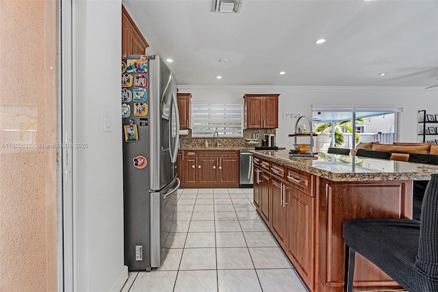 16401 SW 94th St, Miami, FL 33196 - kitchen with stainless steel appliances, ornamental molding, dark stone countertops, decorative backsplash, and a kitchen island with sink