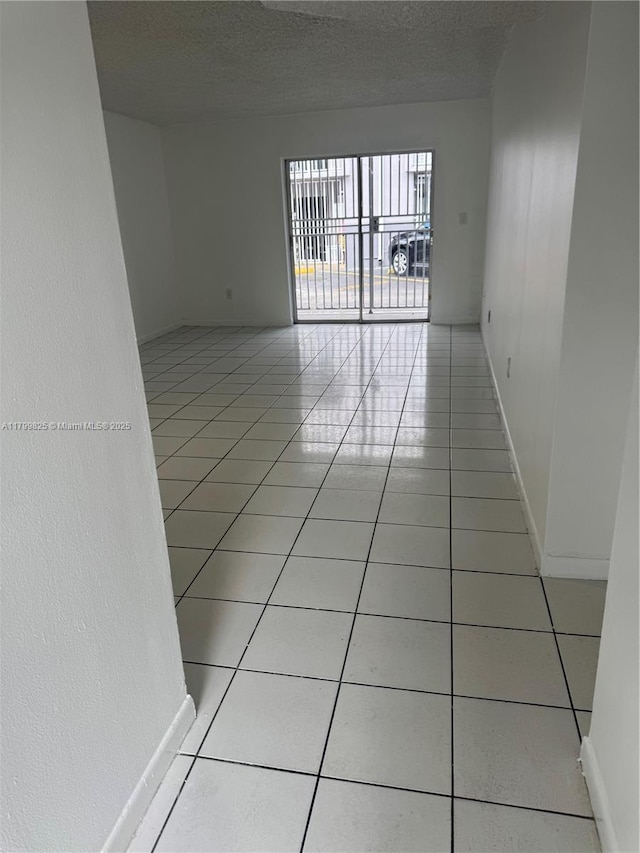 2710 W 76th St Unit 103, Hialeah, FL 33016 - spare room featuring light tile patterned floors, a textured ceiling, and baseboards